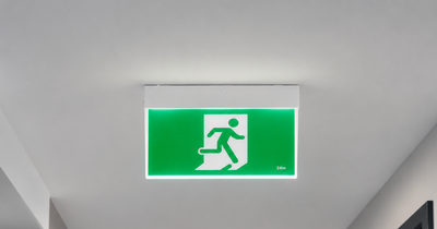 Green emergency exit sign on a ceiling in a hallway